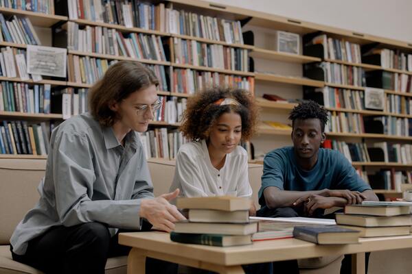 A imagem contém estudantes na biblioteca.