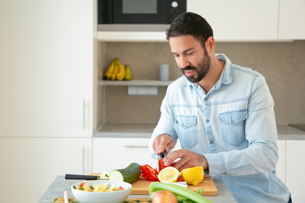 A imagem contém um homem preparando alimentos que aumentam a imunidade.