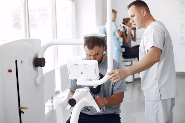 A imagem contém um especialista em Medicina Esportiva fazendo tratamento em máquina com um atleta.