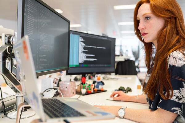 A imagem contém uma profissional formada em Análise e Desenvolvimento de Sistemas programando em seu computador.
