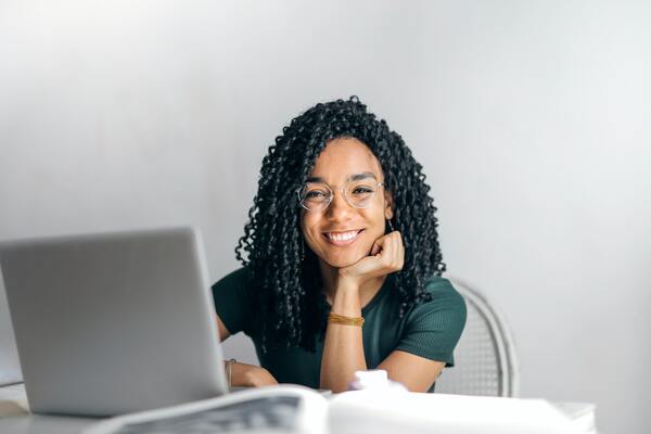 A imagem contém uma estudante feliz porque está com sua rotina de estudos para o Enem organizada.